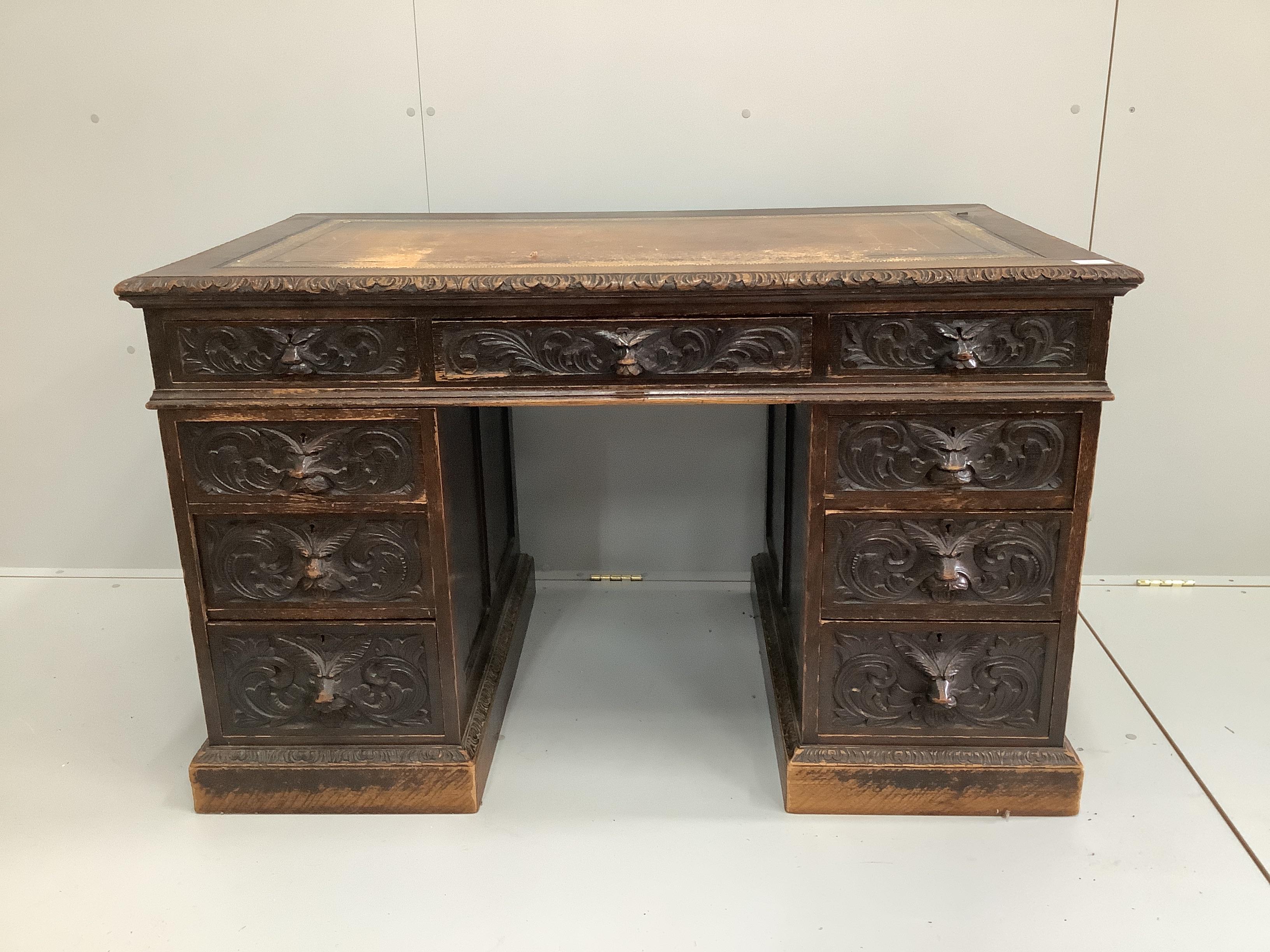 A late Victorian carved oak pedestal desk with lion mask cup handles, width 122cm, depth 70cm, height 75cm